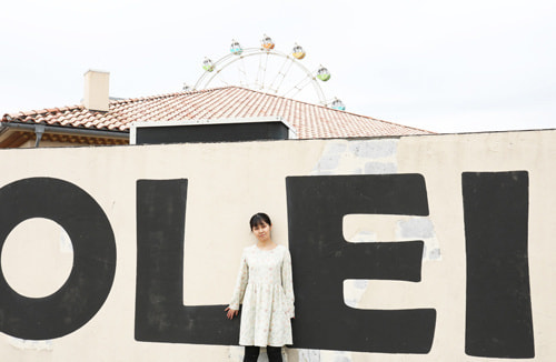 白壁と観覧車の前でポートレート